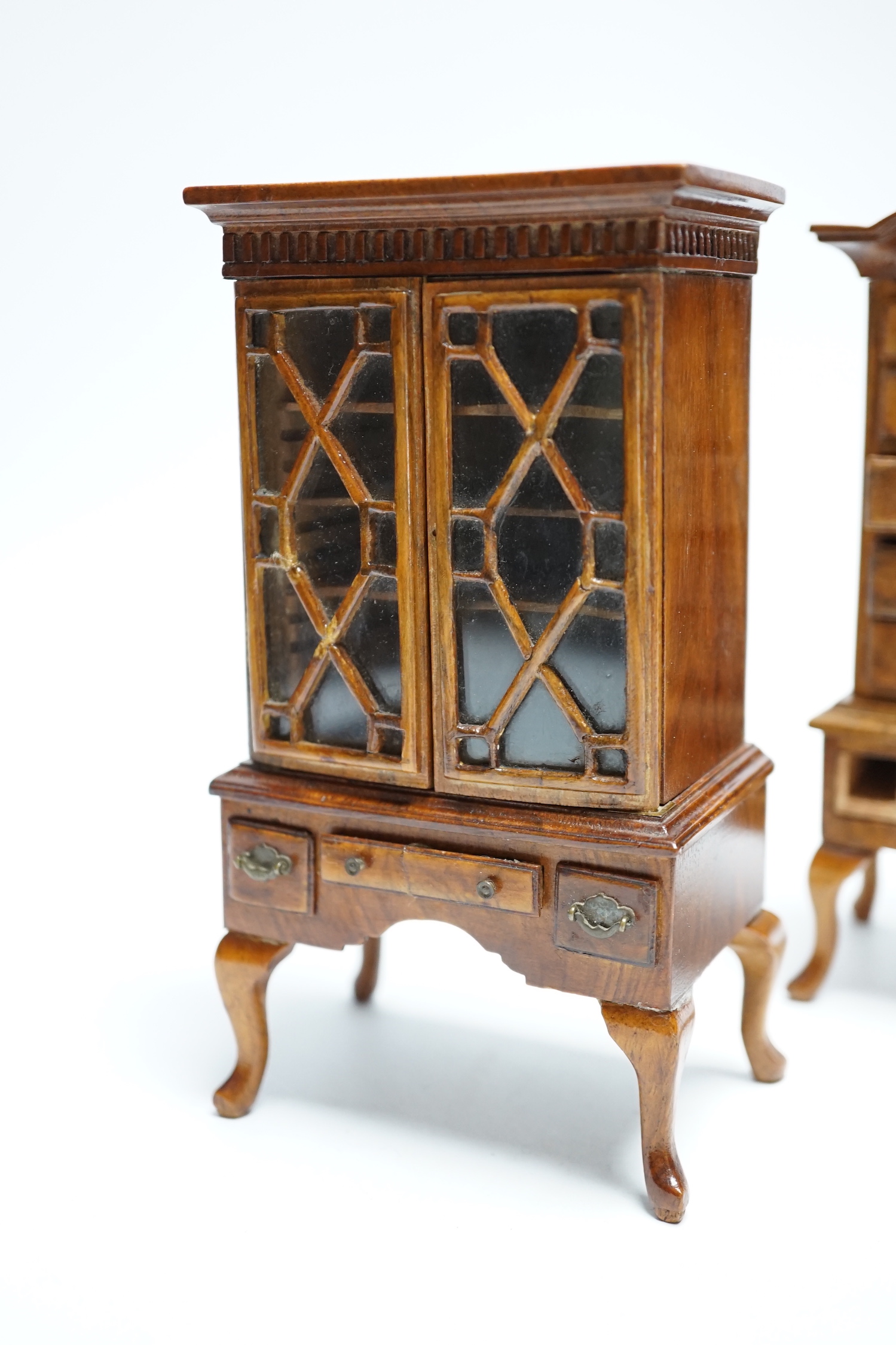 Two pieces of early 20th century miniature furniture - a mid-18th century style walnut bookcase, indistinctly signed on the base (15.5cm high) and a mid-18th century-style walnut chest on stand (16cm high). (Provenance B